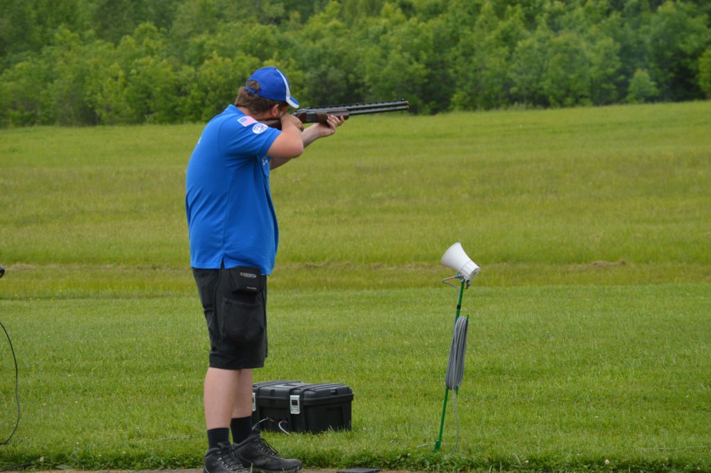 With his back to the camera, Connor Wight shoots trap on a green lawn.